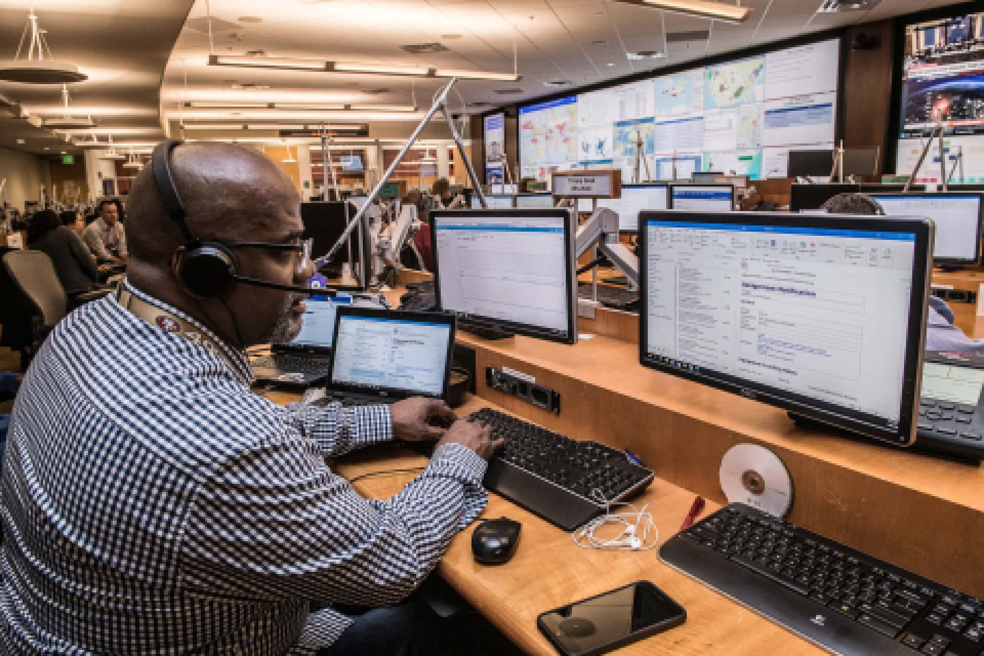 African American man working in front of three computer screens.